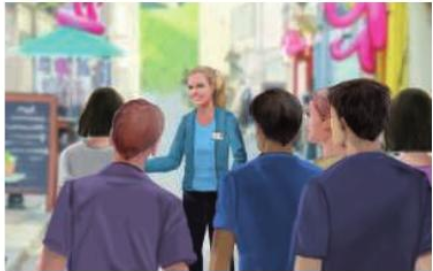 Une guide parle à un groupe de touristes dans une rue commerçante.