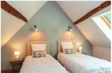 Chambre B : deux lits simples sous les toits, avec poutres en bois apparentes et fenêtre de toit.